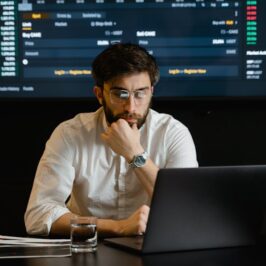 Homme devant un ordinateur et en arrière plan des indicateurs économiques