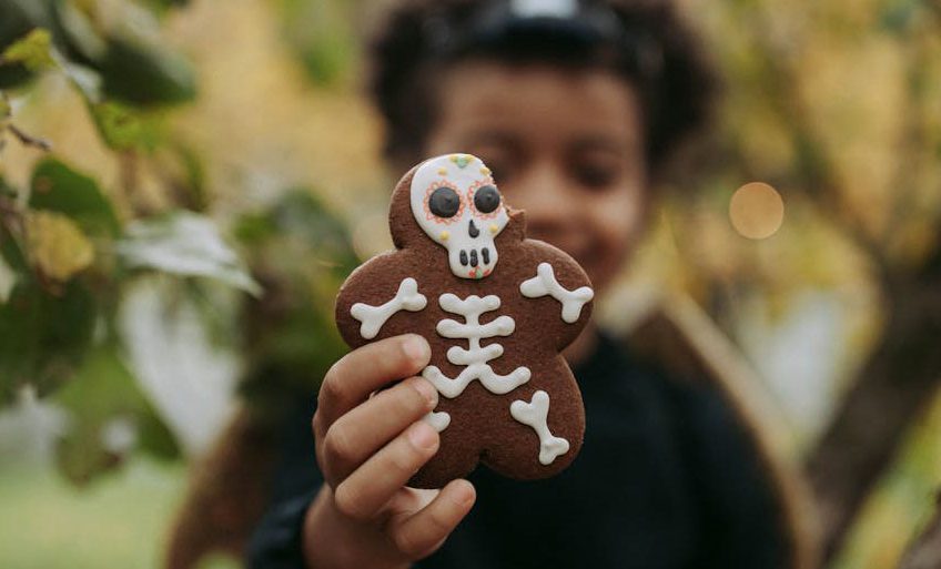 Enfant tenant dans sa main un biscuit en forme de squelette